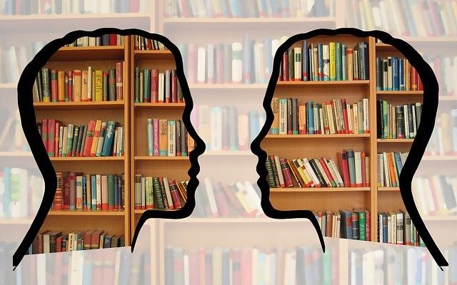 Twarze skierowane do siebie, w tle regały książek.