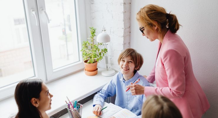 Nauczyciel i dzieci odrabiające lekcje.