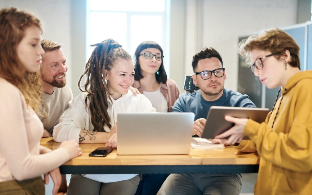 Młodzież wraz z nauczycielami pracująca podczas lekcji na laptopie i tablecie