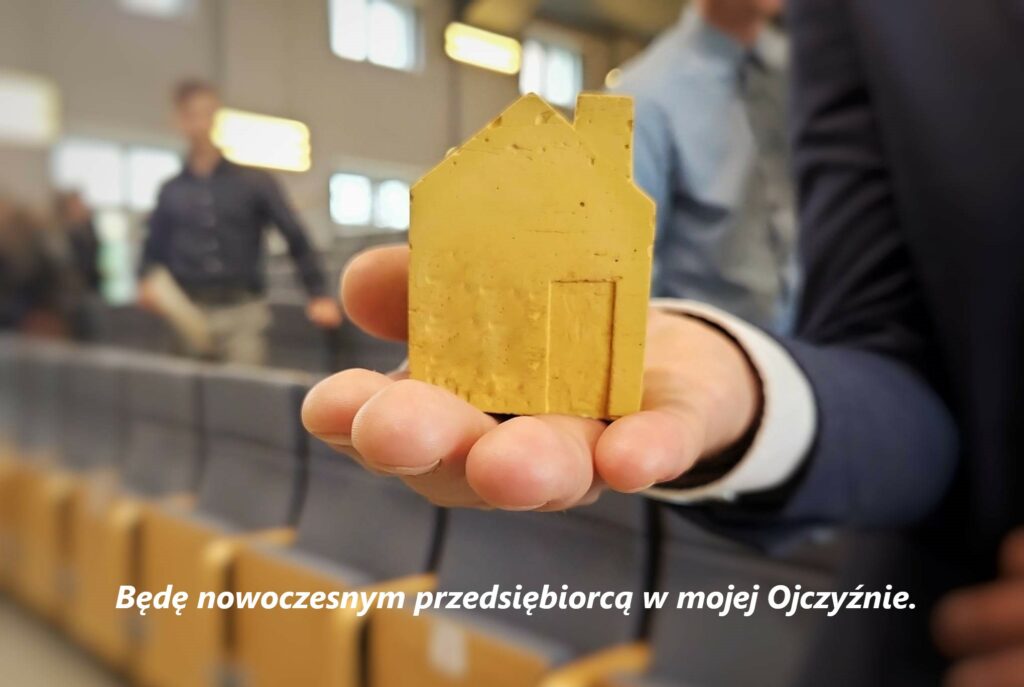 Zdjęcie główne - konferencja pt. Biznes i zarządzanie – praktyczny wymiar nauczania przedsiębiorczości- żółty domek na ręce uczestnika konferencji