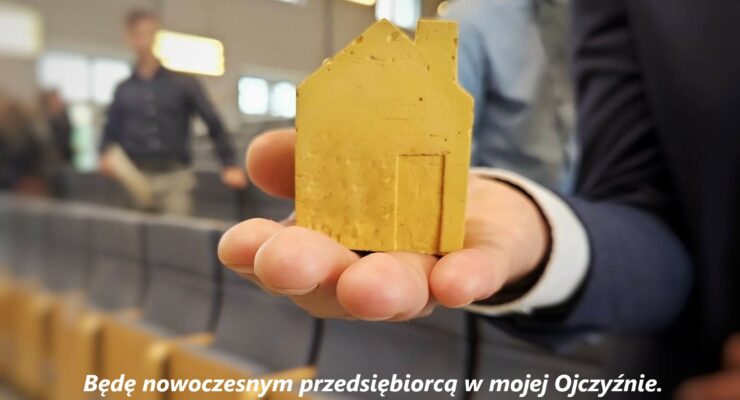 Zdjęcie główne - konferencja pt. Biznes i zarządzanie – praktyczny wymiar nauczania przedsiębiorczości- żółty domek na ręce uczestnika konferencji