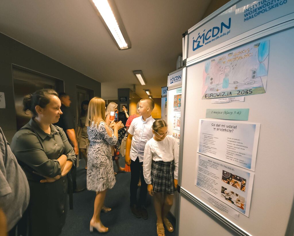 Rodzice i dzieci oglądający wystawę prac konkursowych.