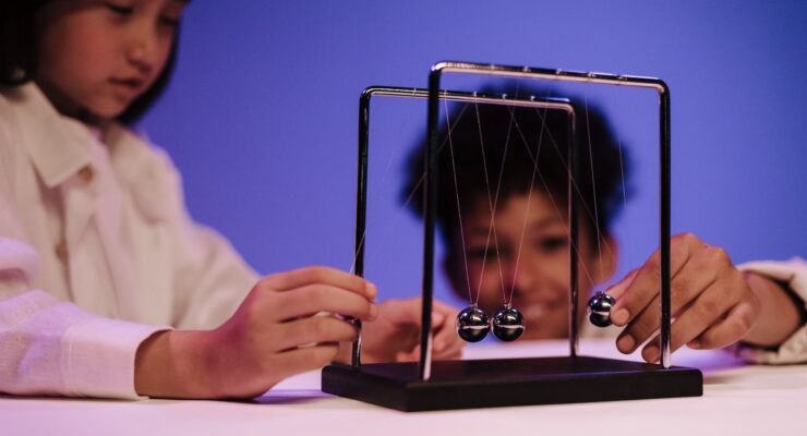 Dziewczynka i chłopiec obserwujący wahadło Newtona