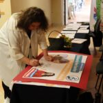 Anna Dymna składająca autograf na plakacie konferencyjnym