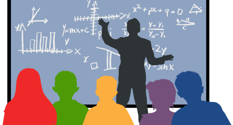 grafika przedstawia zarys postać nauczyciela przy tablicy oraz zarysy uczniów