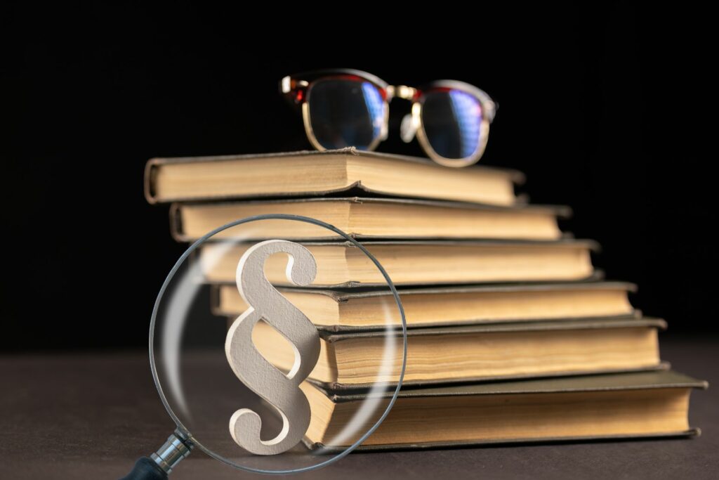 lupa, paragraf, stos książek, okulary