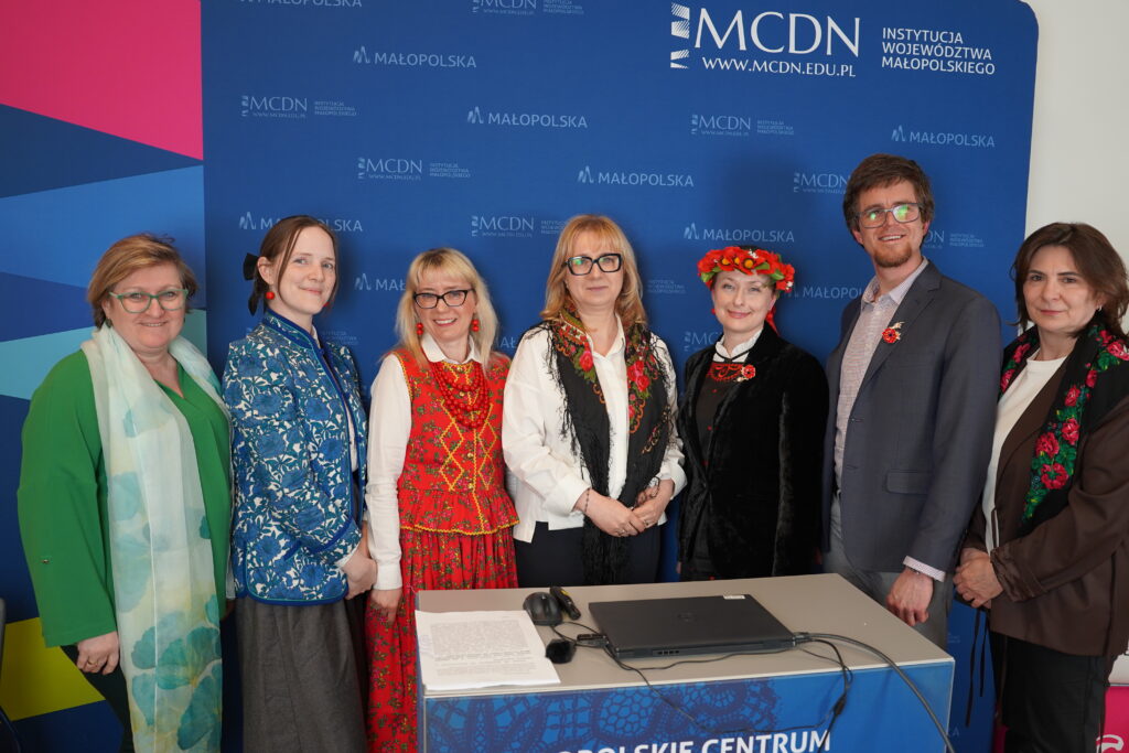 Na tle banneru MCDN: dr Małgorzata Dutka-Mucha, wicedyrektor Małopolskiego Centrum Doskonalenia Nauczycieli w Krakowie i prelegenci konferencji